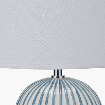 Table lamp with striped base and gray shade on a light gray background