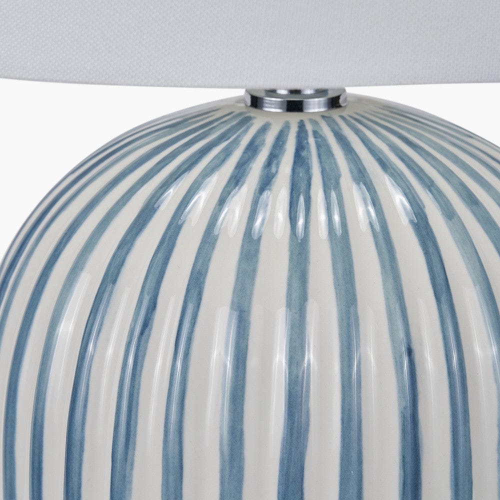 Close-up of a striped lampshade with blue and white vertical stripes on a gray background