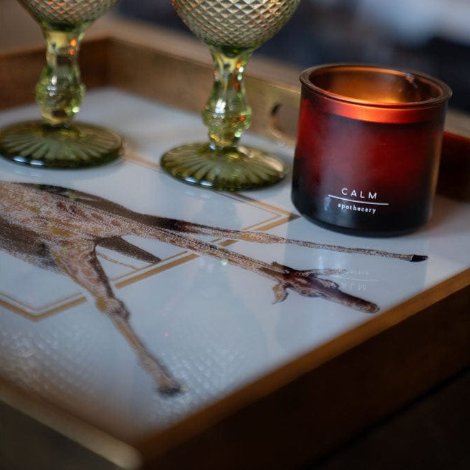 Two decorative glasses and a 'Calm' candle on a decorative giraffe tray