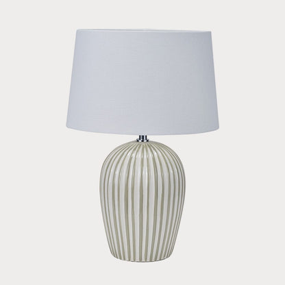 Table lamp with a striped ceramic base and white shade on a white background