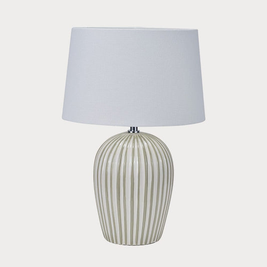 Table lamp with a striped ceramic base and white shade on a white background