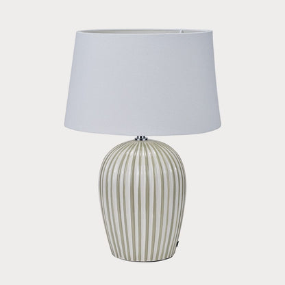 Table lamp with a striped base and white shade on a white background