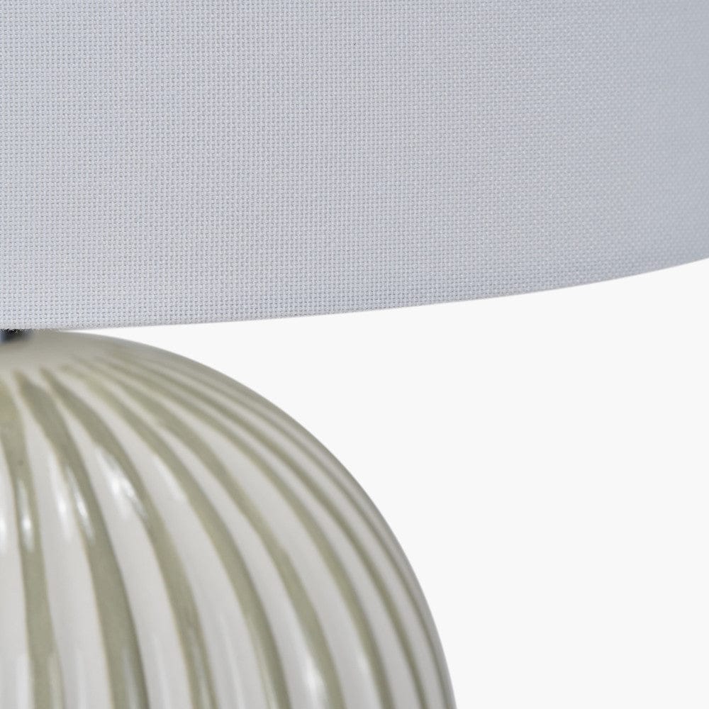 Close-up of a textured lampshade and base on a light gray background