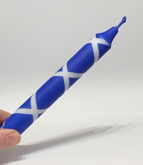 Blue and white striped scotland flag dinner candle held by a hand on a light gray background