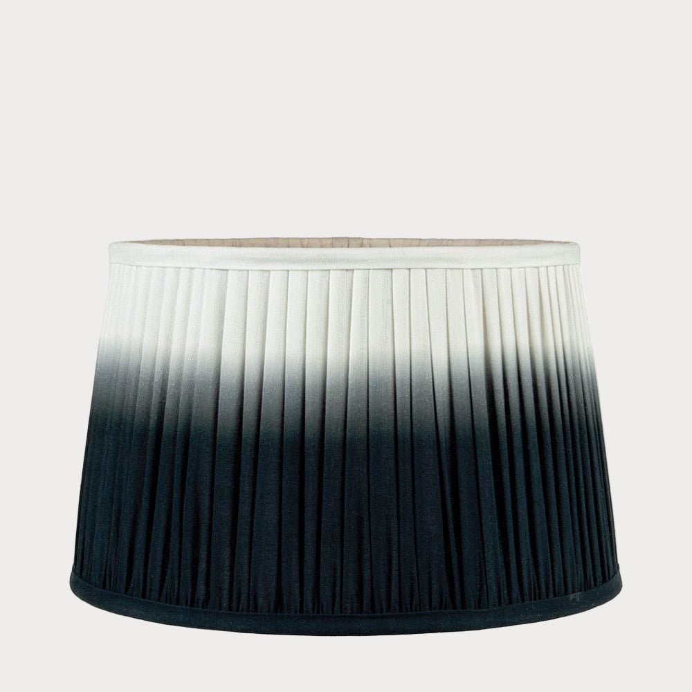 A pleated tapered shade with a ombre gradient color design, transitioning from white to black.
