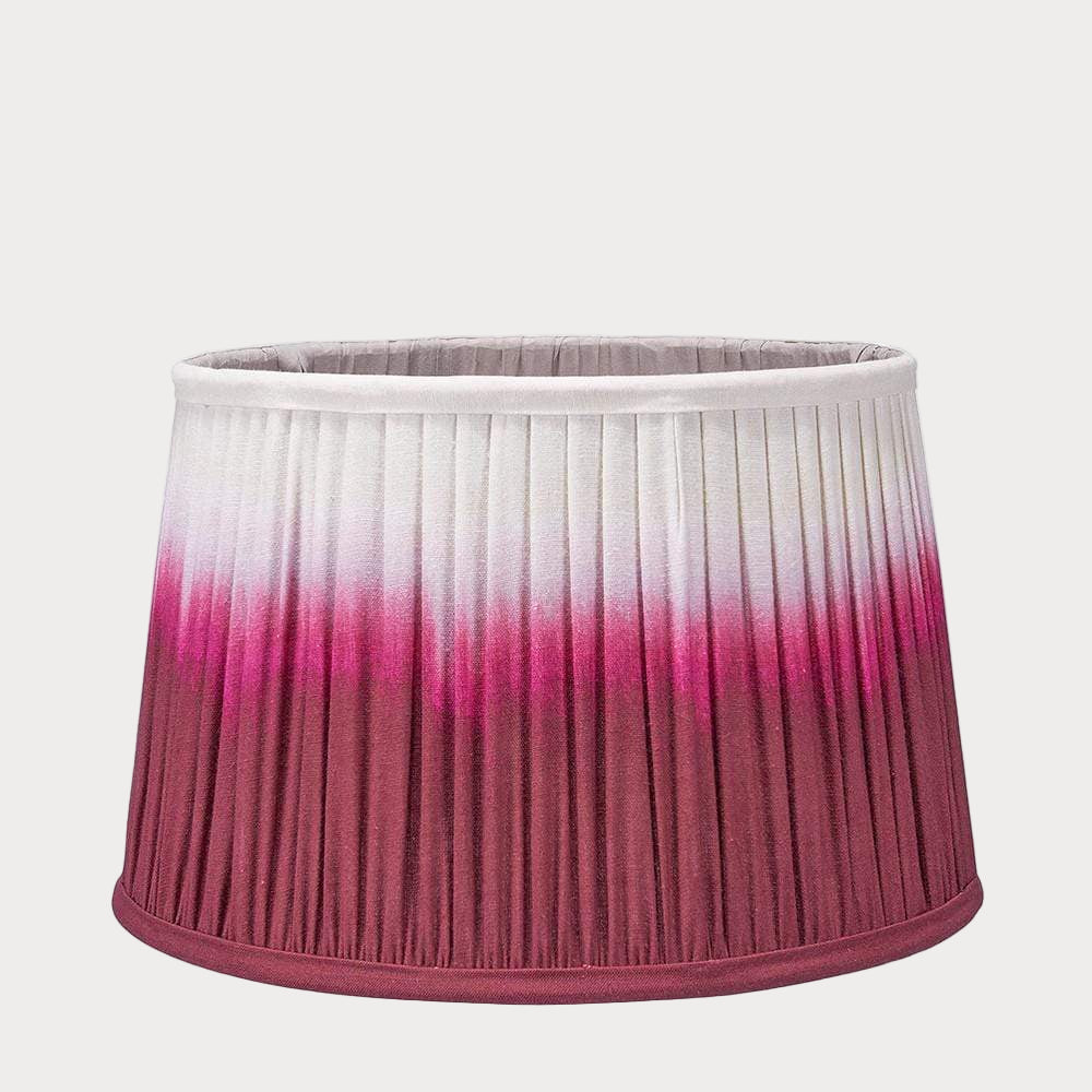 A pleated tapered shade with a ombre gradient color design, transitioning from white to raspberry red.