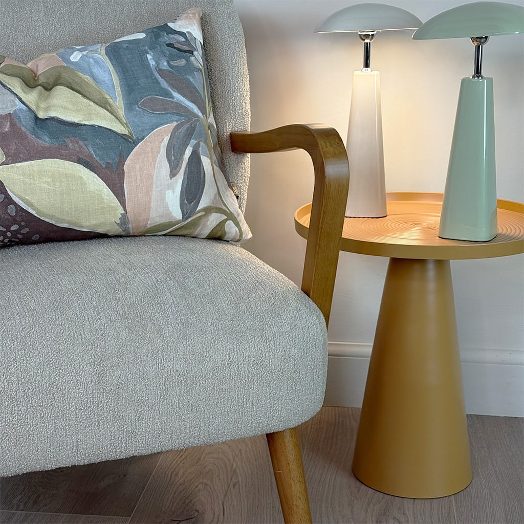 Gray armchair with a decorative pillow next to a wooden side table with two lamps.