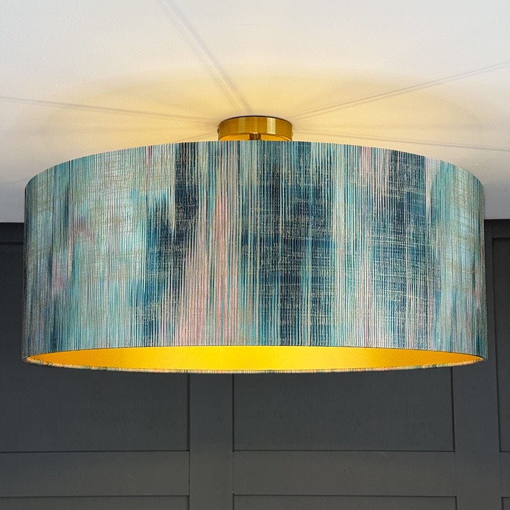 Ceiling light fixture with a colorful drum shade against a dark wall.