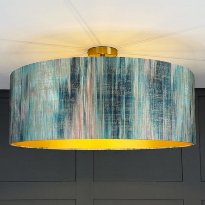 Ceiling light fixture with a colorful drum shade against a dark wall.