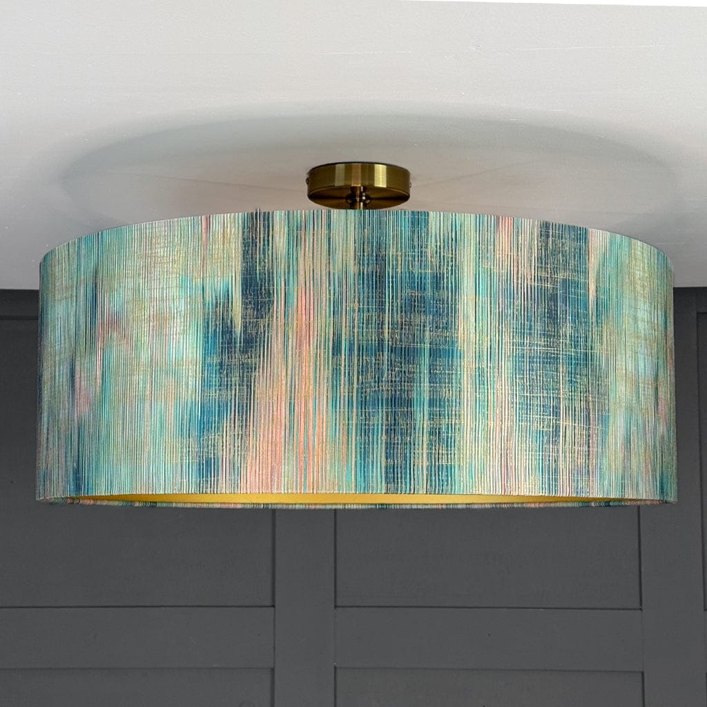 Ceiling light fixture with a colorful cylindrical shade against a gray wall.