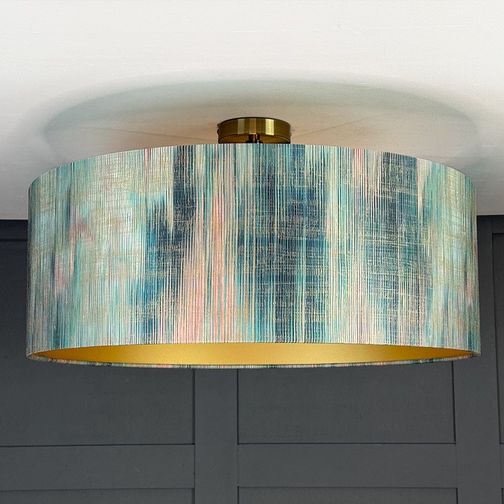 Ceiling light fixture with a colorful drum shade against a gray wall.