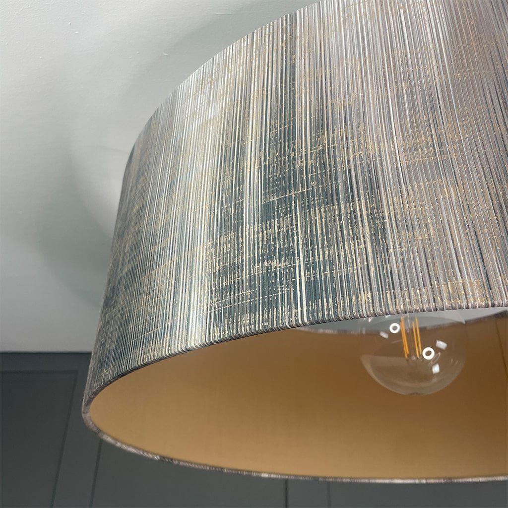Close-up of a textured lampshade with a light bulb inside, on a neutral background.