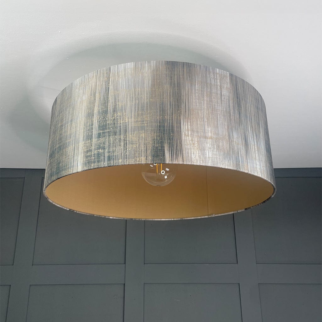 Ceiling light fixture with a textured silver shade on a gray wall background