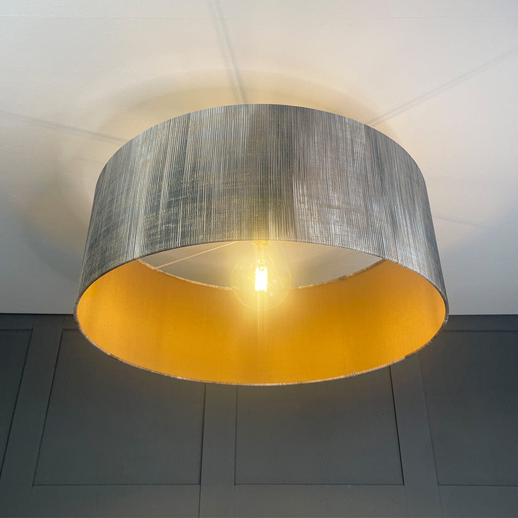 Ceiling light fixture with a metallic shade on a neutral background