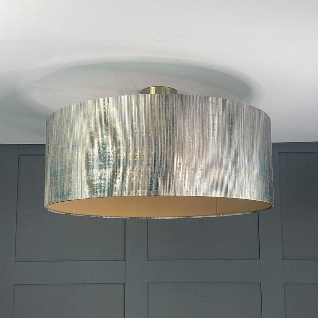 Ceiling light fixture with a textured drum shade against a gray wall.