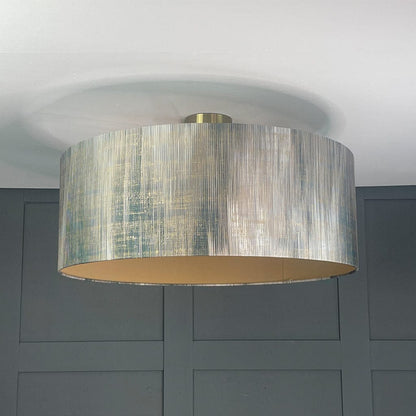 Ceiling light fixture with a textured drum shade against a gray wall.