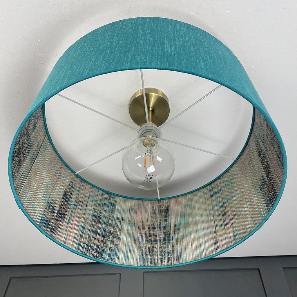 Ceiling light fixture with teal and patterned shades on a white ceiling.