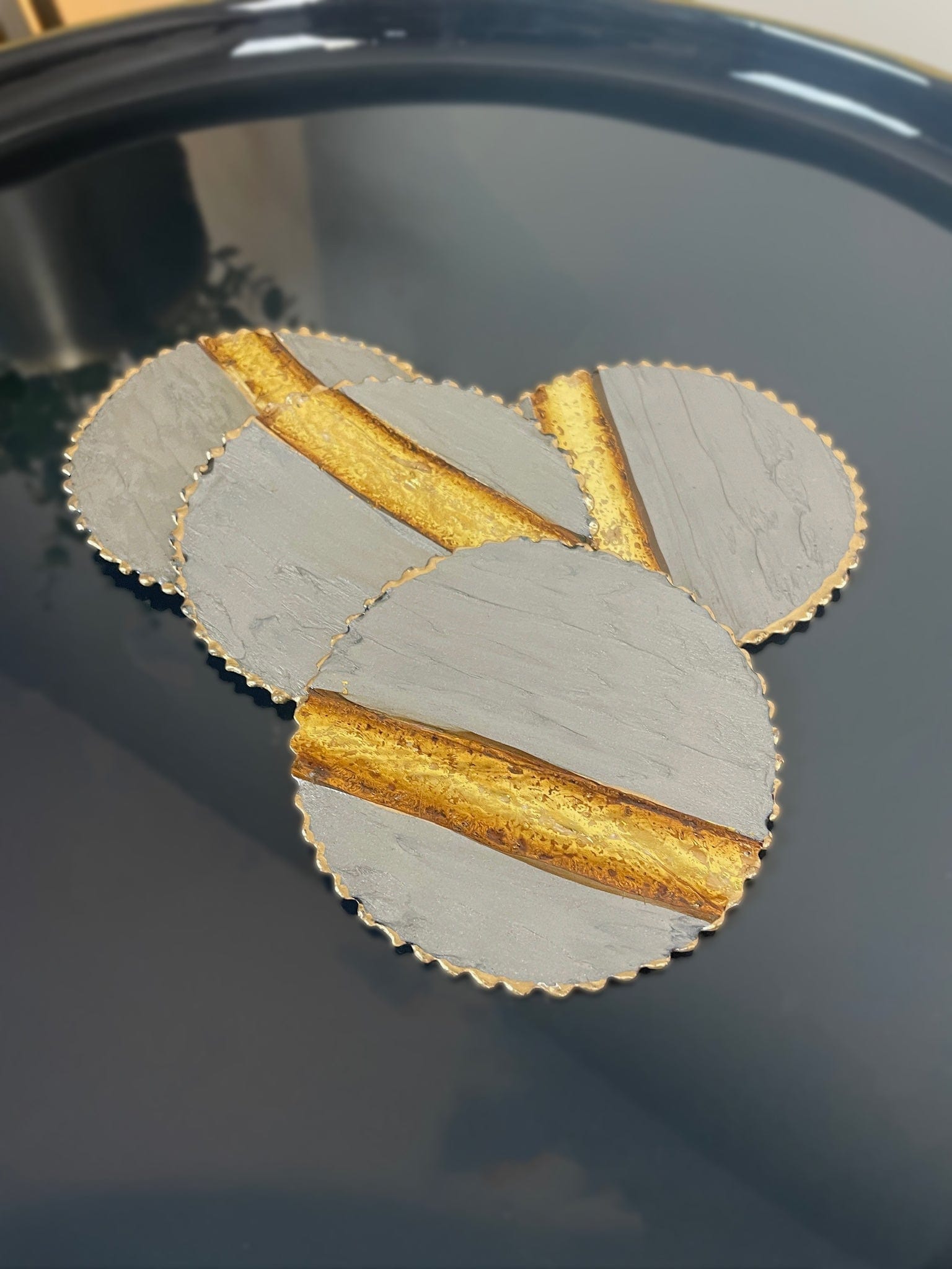 Decorative coasters with gold and gray design on a dark surface