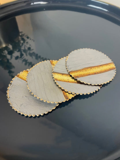 Three circular coasters with gold edges on a dark surface