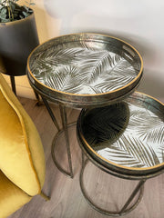 Two round side tables with leaf pattern on a wooden floor.