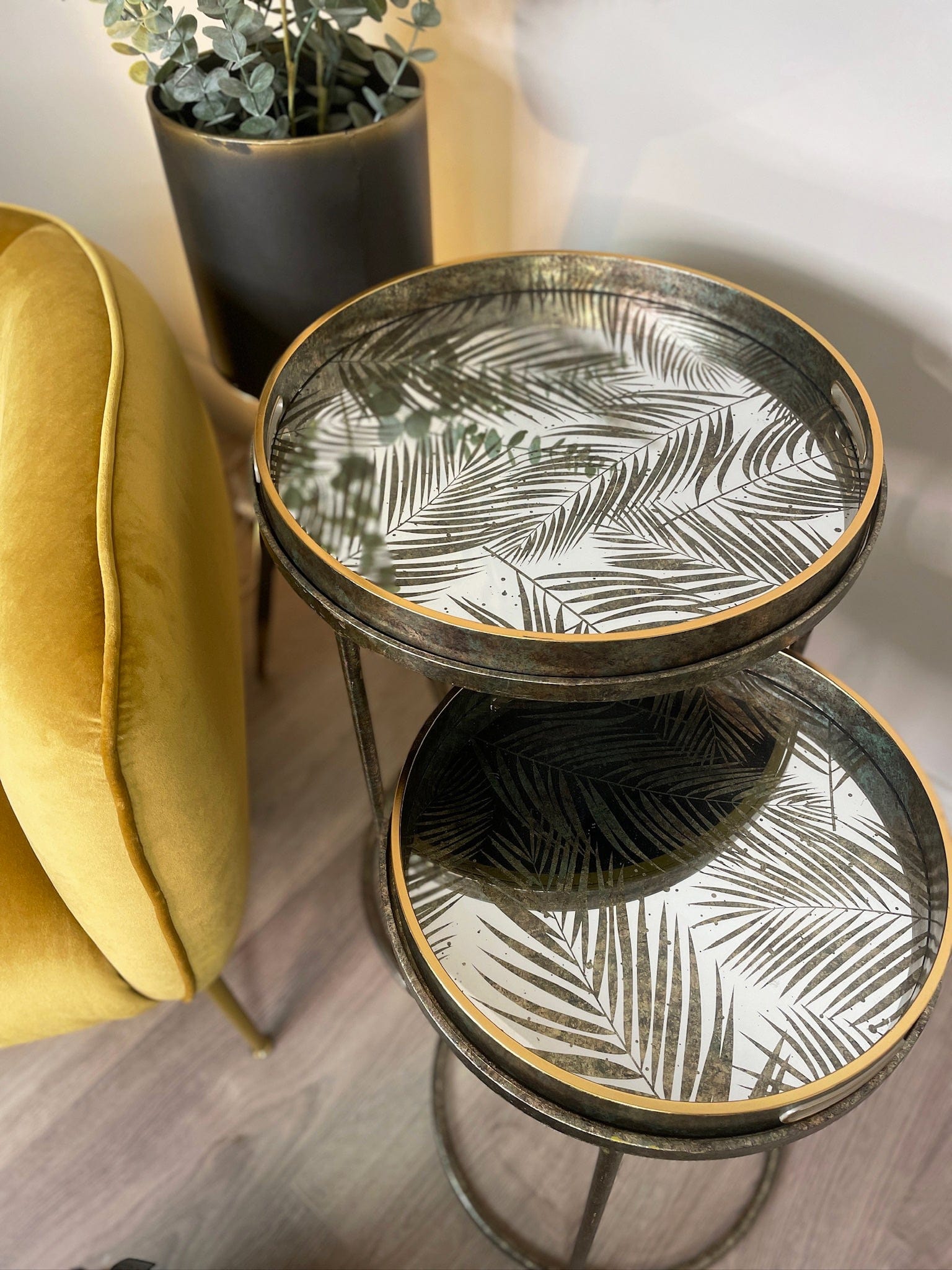 Small round table with leaf pattern next to a yellow cushioned chair.