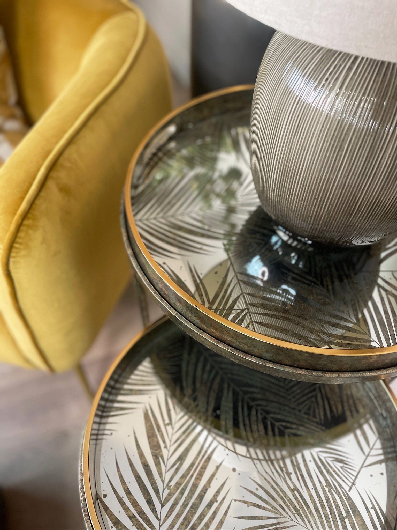 Decorative fern leaf glass table next to a yellow armchair
