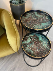 Round marble-patterned nest of tables with gold edges next to a yellow chair.