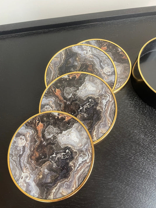 Marble-patterned coasters with gold edges on a black surface