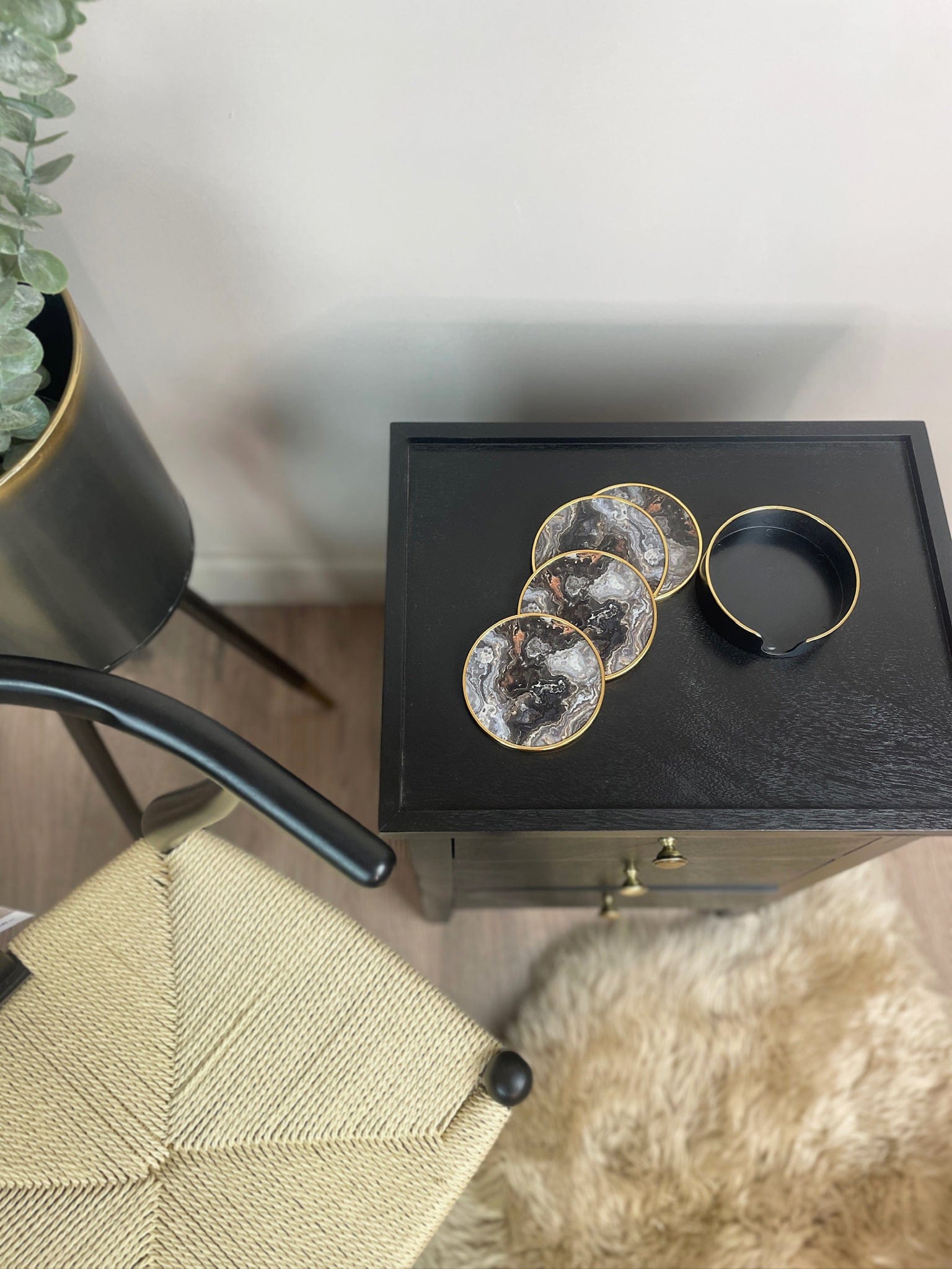 Decorative coasters on a black box with a plant and chair in the background