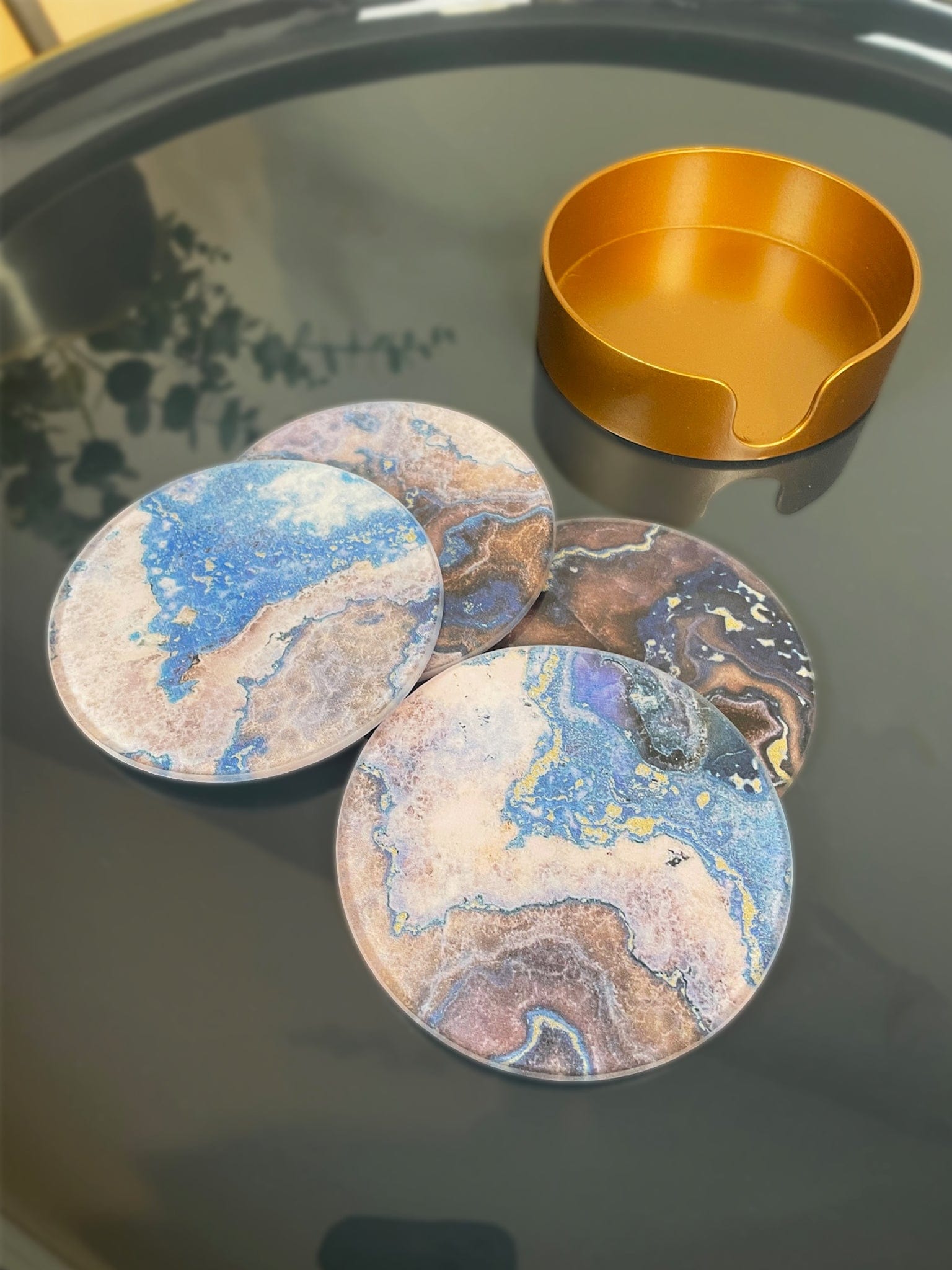 Marble-patterned coasters on a reflective surface with a bronze bowl.
