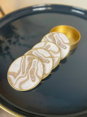 Set of coasters with gold and white design on a dark surface