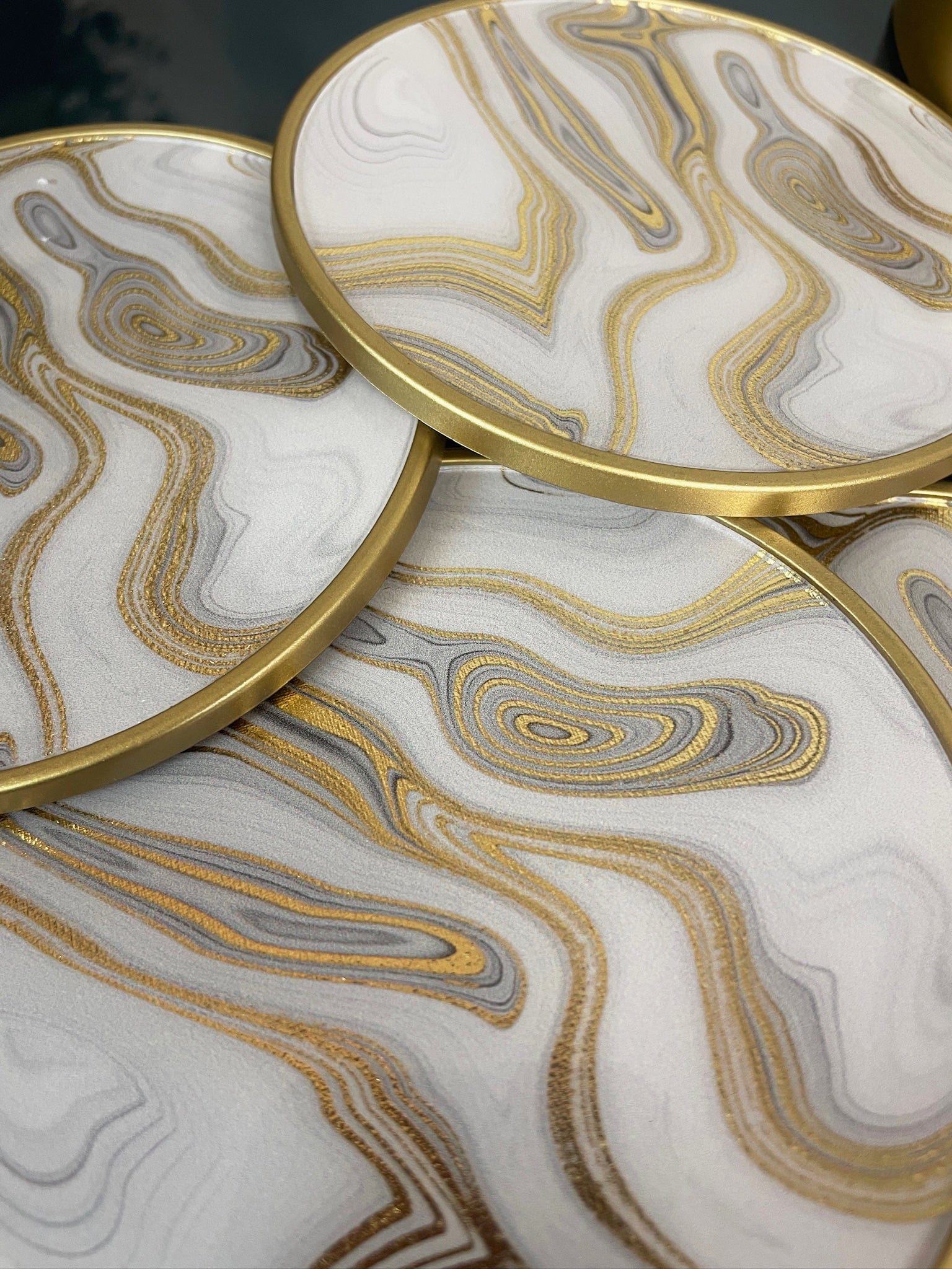Marble-patterned coasters with gold edges on a matching surface.