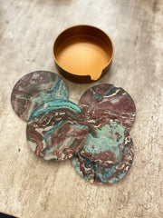 Set of marbled coasters with a copper container on a textured surface