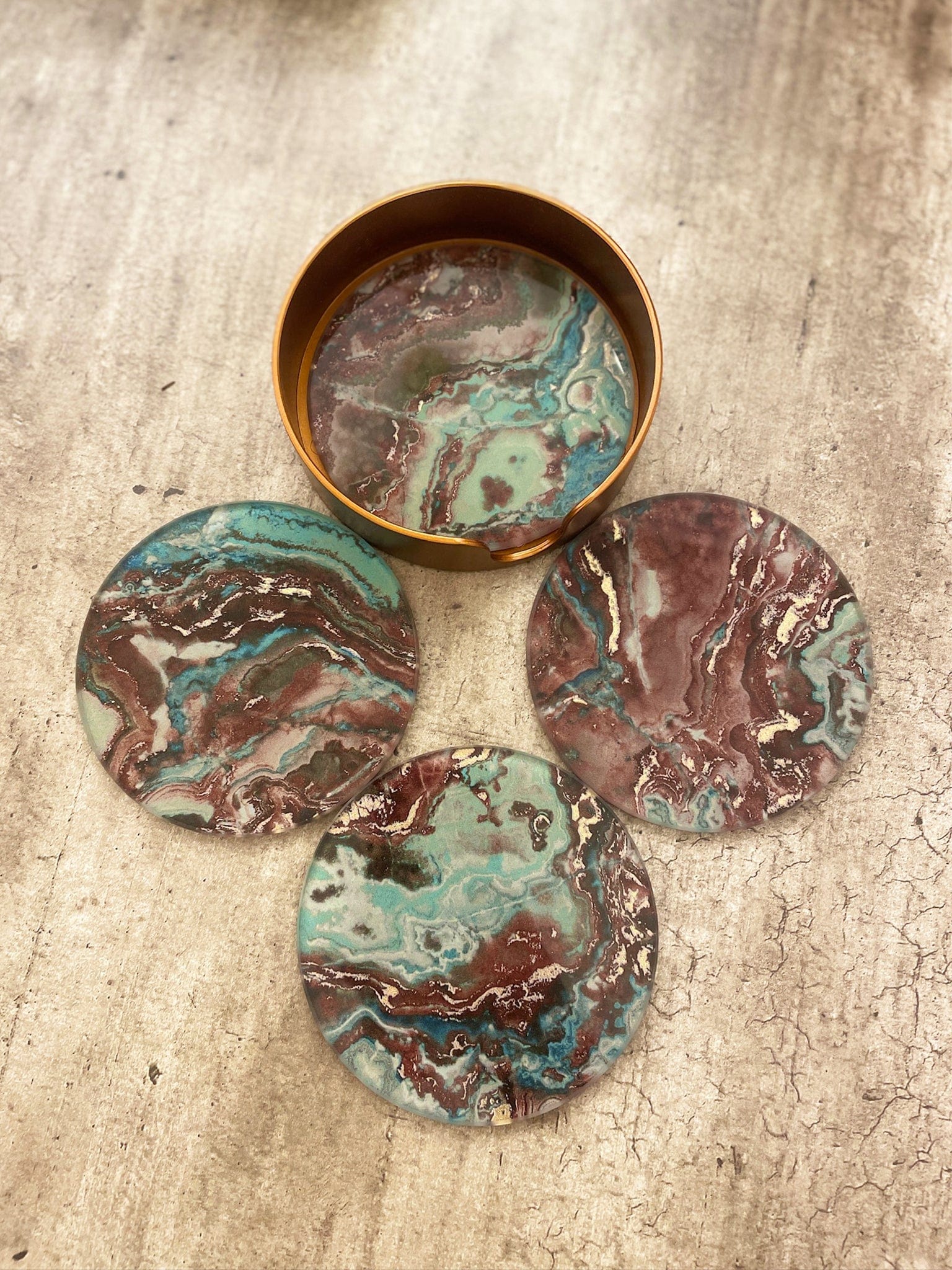 Set of marbled coasters in a round container on a textured surface