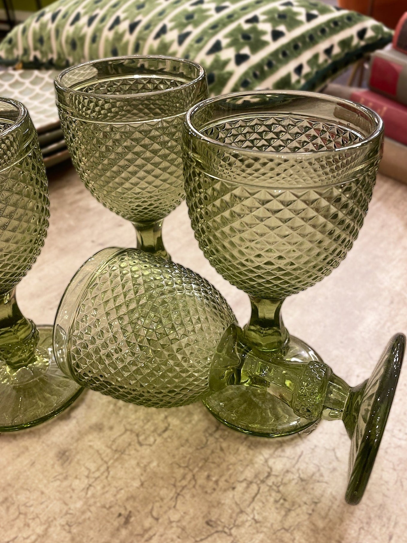 Set of green textured glass goblets on a patterned surface
