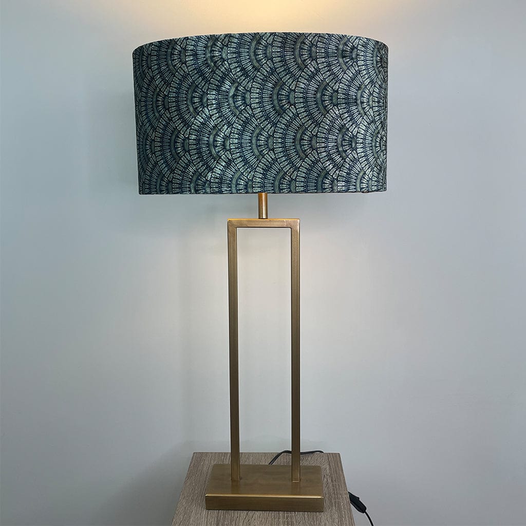Table lamp with a patterned navy blue and gold shade on a brass base against a light gray background