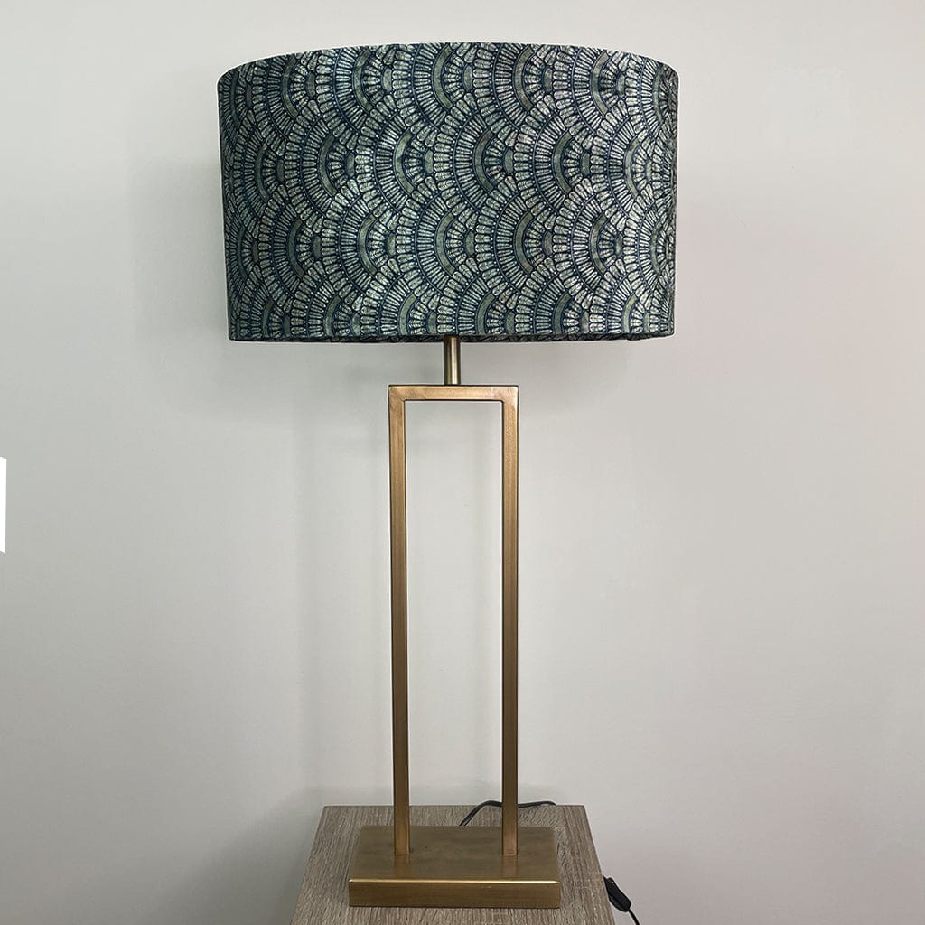 Table lamp with a patterned navy and gold shade on a gold base against a light gray background