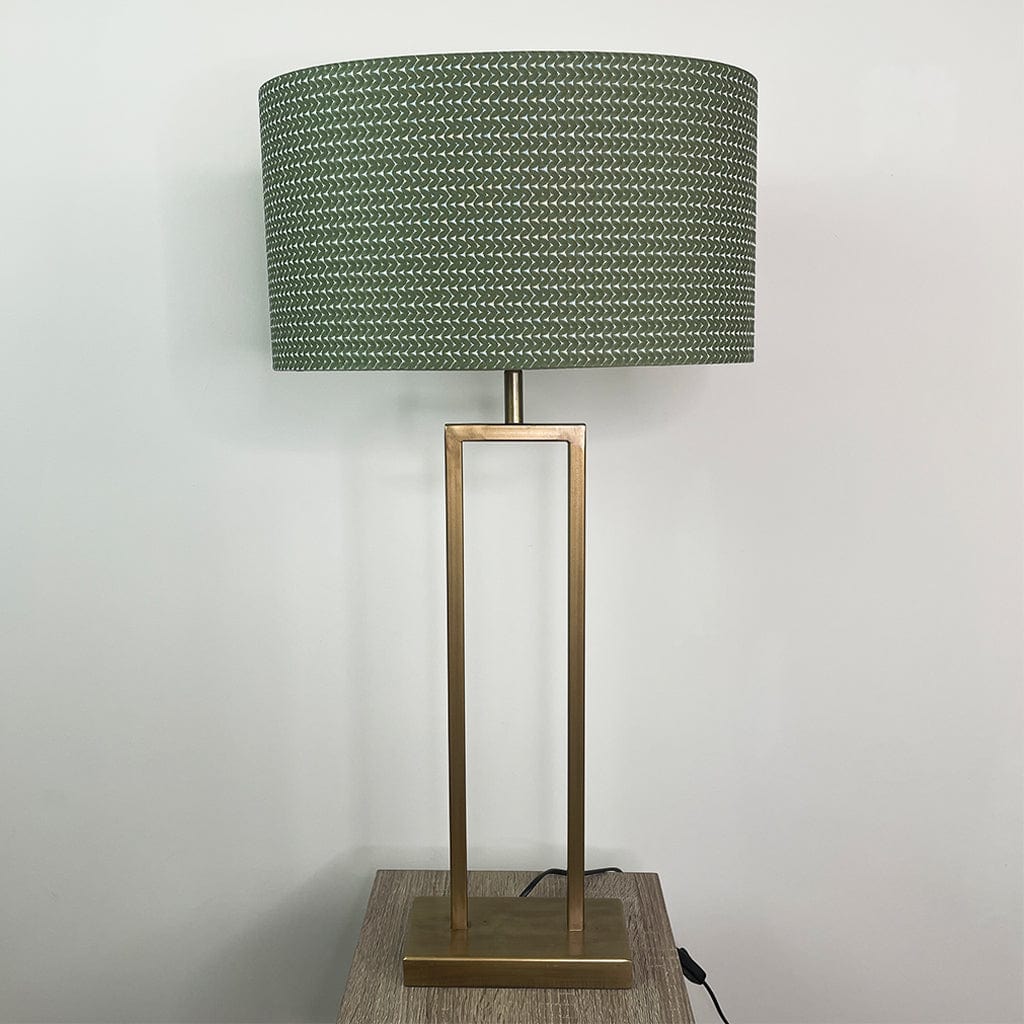 Table lamp with a green textured shade and brass base on a wooden surface.
