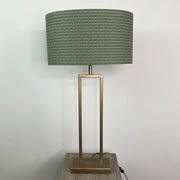 Table lamp with a green textured shade and brass base on a wooden surface.