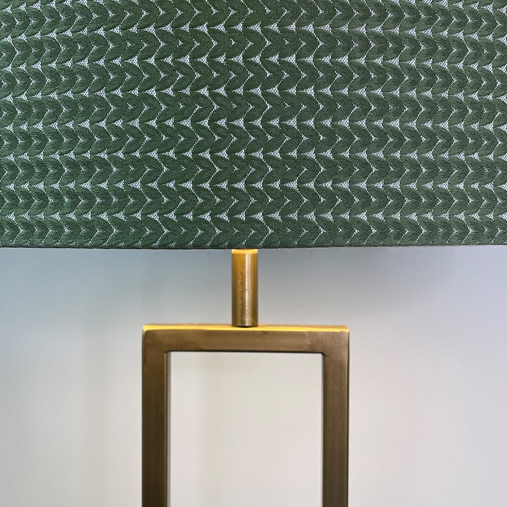 Lamp with green textured shade and brass base on a light gray background