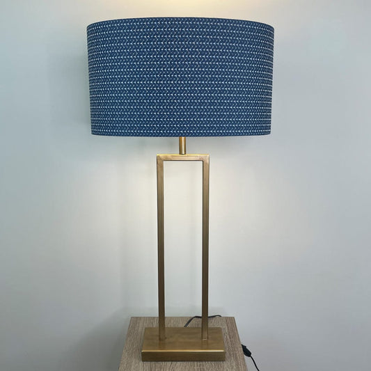 Table lamp with a blue patterned shade and gold base on a wooden surface.