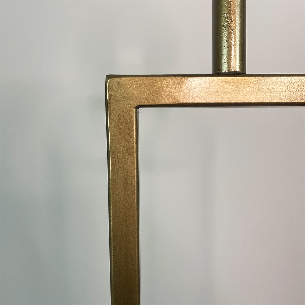 Close-up of a brass square frame against a light gray background