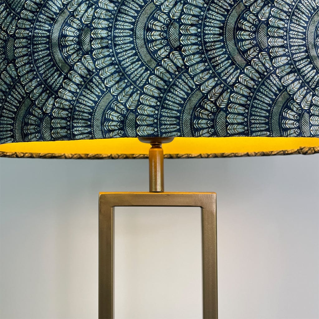 Lamp with a decorative blue and gold Art Deco velvet lampshade on a plain background