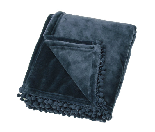 A folded slate blue cashmere touch fleece throw with pom pom trim on the edge.