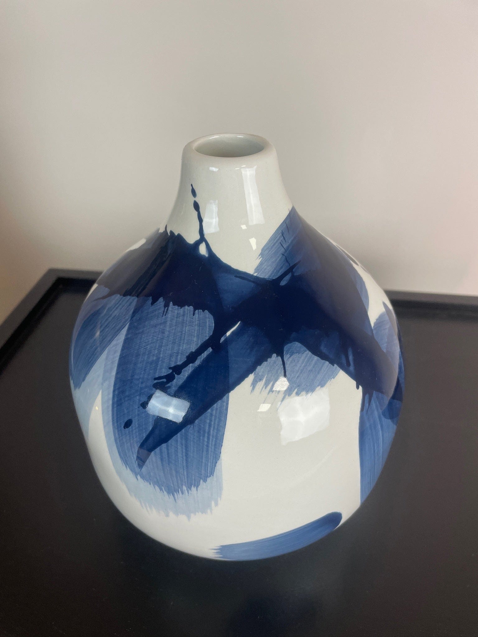 White vase with blue abstract patterns on a black surface