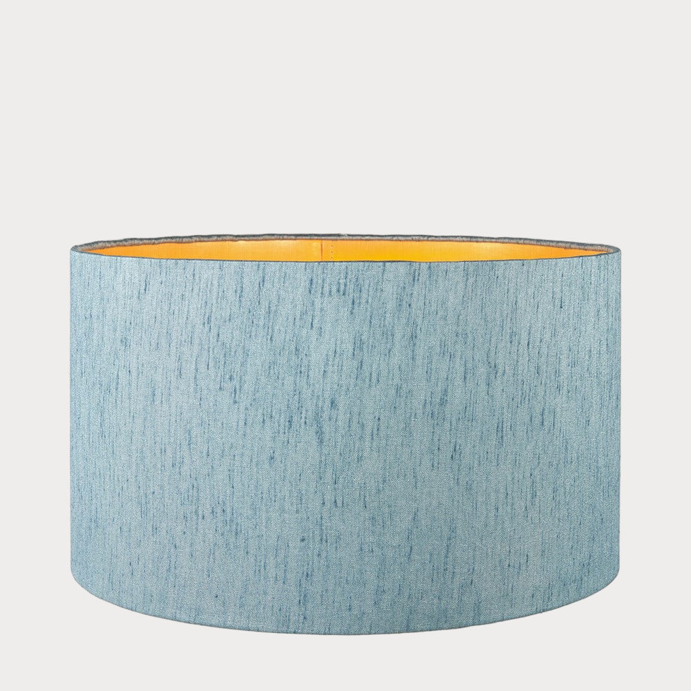 A cylindrical lampshade with a slubbed faux silk texture and a gold interior lining.