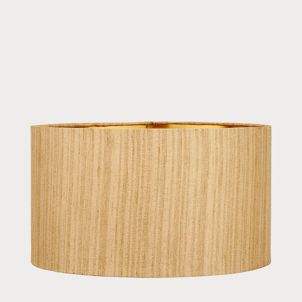 A cylindrical lampshade with a slubbed faux silk texture and a gold interior lining.