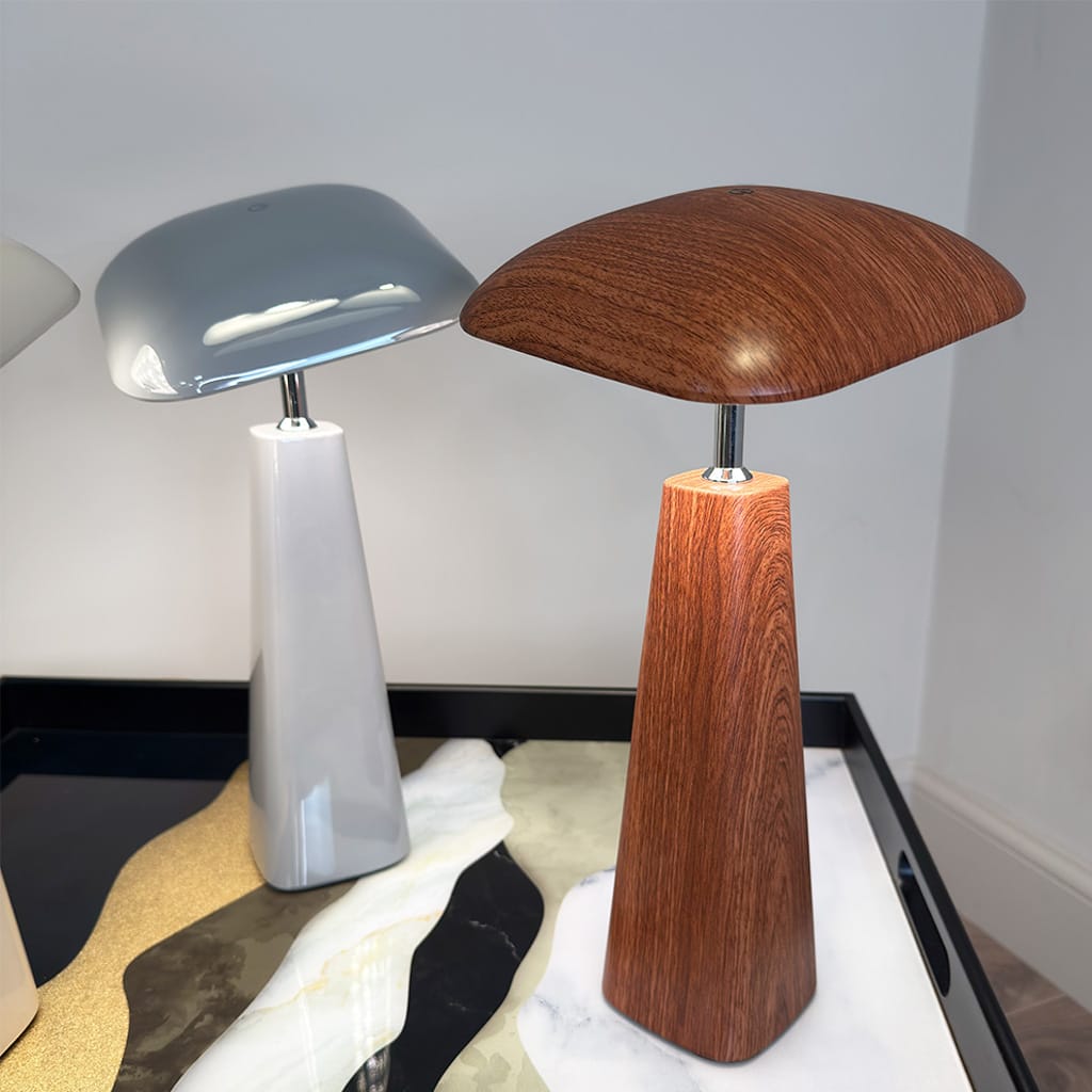 Two table lamps, one with a wooden base and the other with a metallic base, on a white surface.