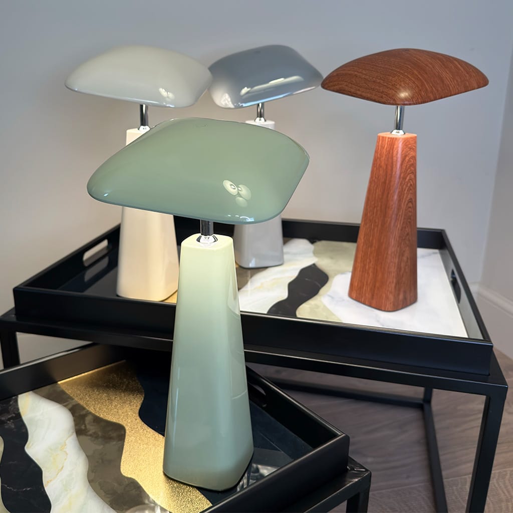 Three table lamps with different designs on a black tray against a neutral background