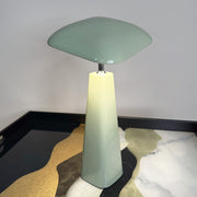 Modern table lamp with a green shade and base on a textured surface.